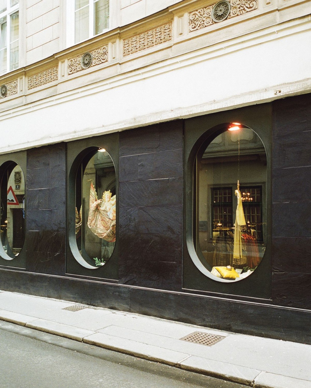 Street-level shop windows with sleek black frames display ornate dresses on mannequins. The building's classical facade features decorative details.