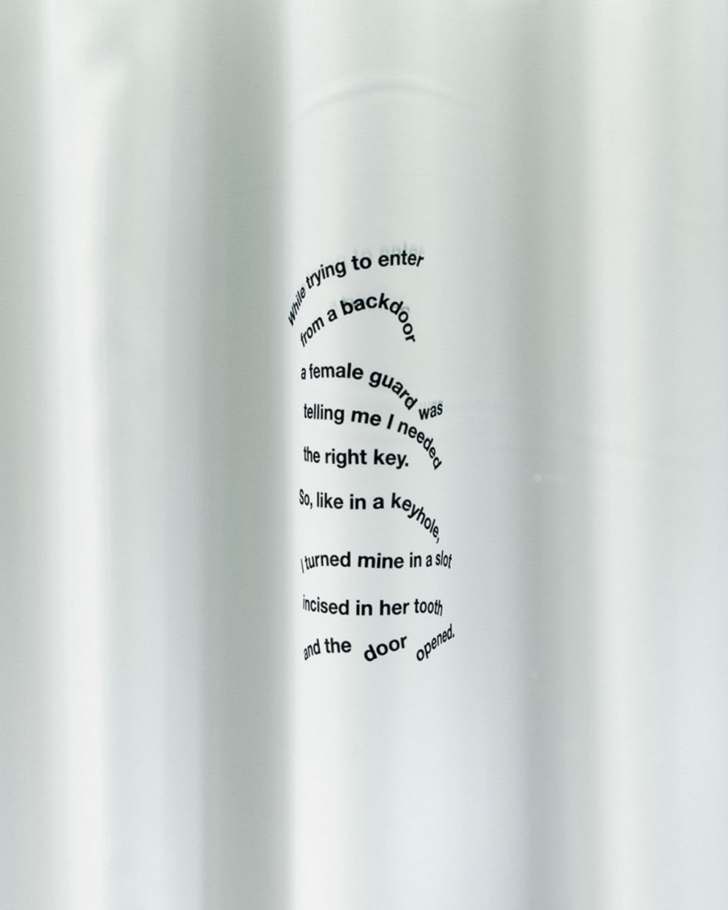 Curved black text on a smooth, light gray surface resembles a poem or story about needing the right key. The text forms a wave pattern, creating a sense of flow.