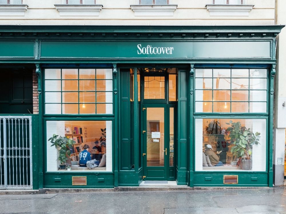 Green storefront of a bookstore named "Softcover" with large windows.