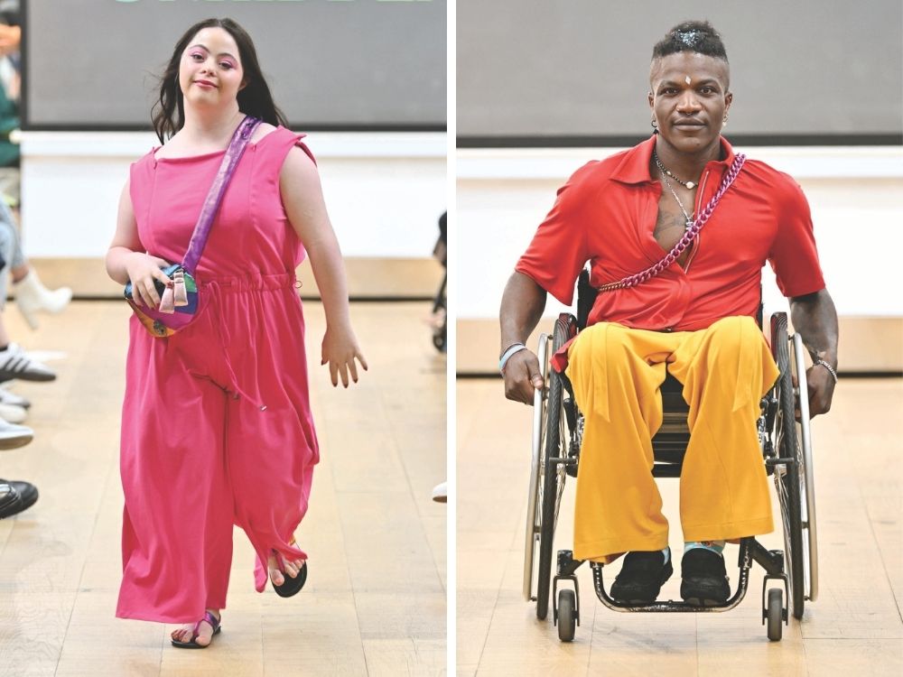 A woman in a pink dress and a man in a red shirt with yellow pants, using a wheelchair. Both are confidently walking on a wooden runway.