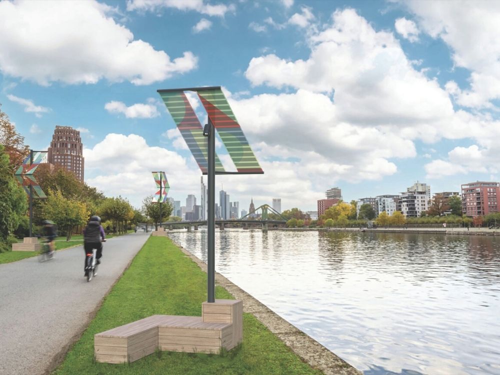 A man rides a bike along a river, passing a sign that reads "solar," highlighting eco-friendly energy.